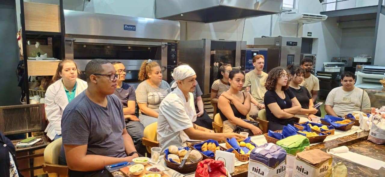 Um grupo de pessoas está sentado ao redor de uma mesa na cozinha.