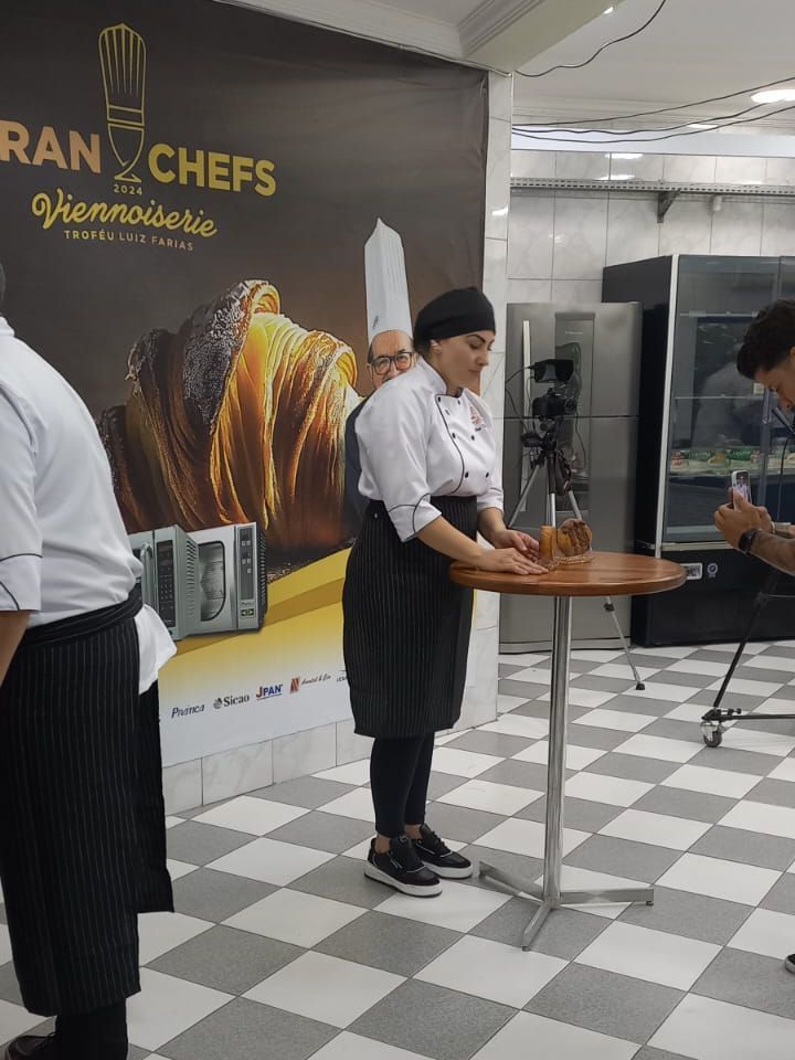 Um grupo de chefs estão em volta de uma mesa na cozinha.