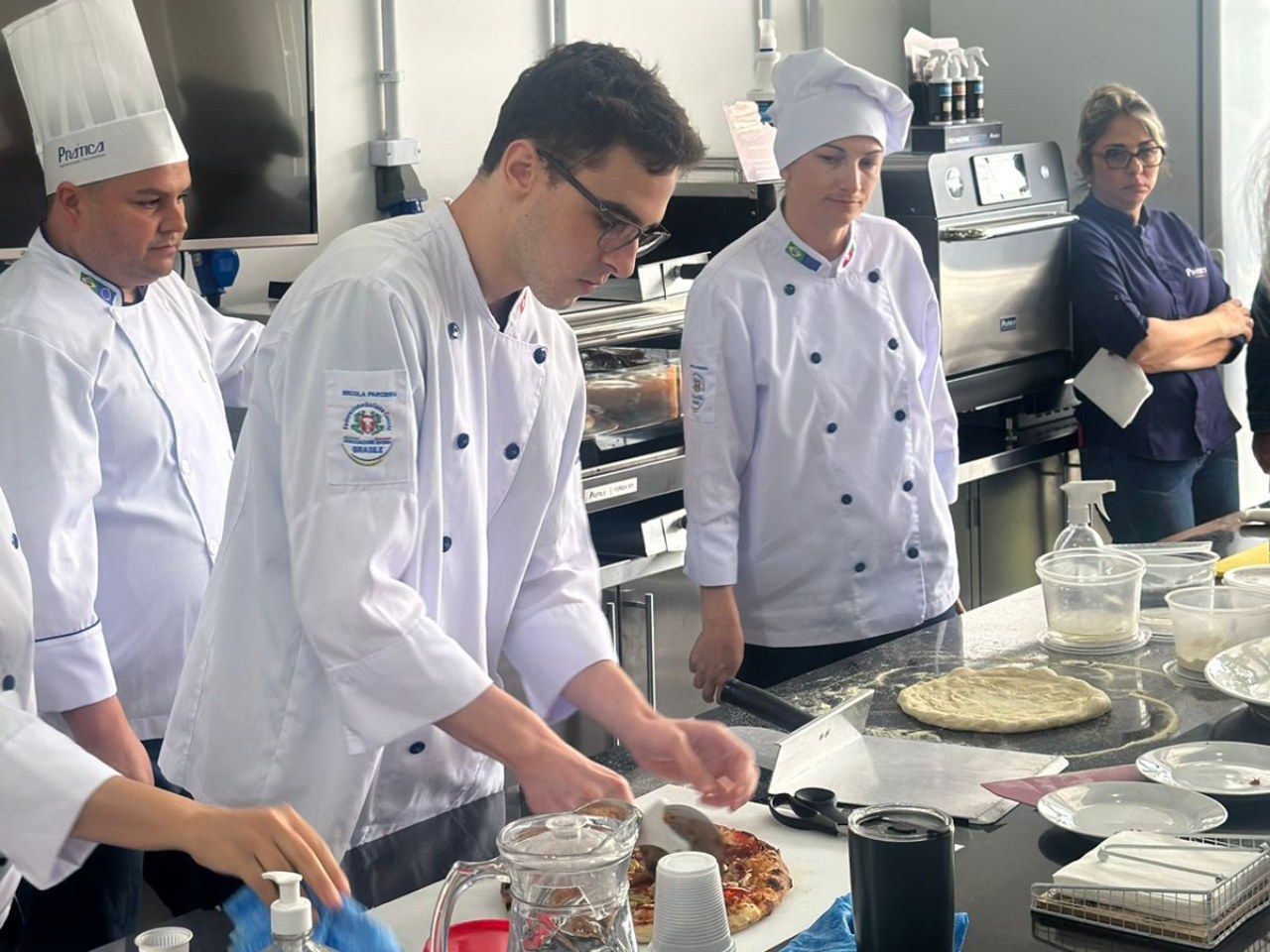 Um grupo de chefs está preparando comida em uma cozinha.