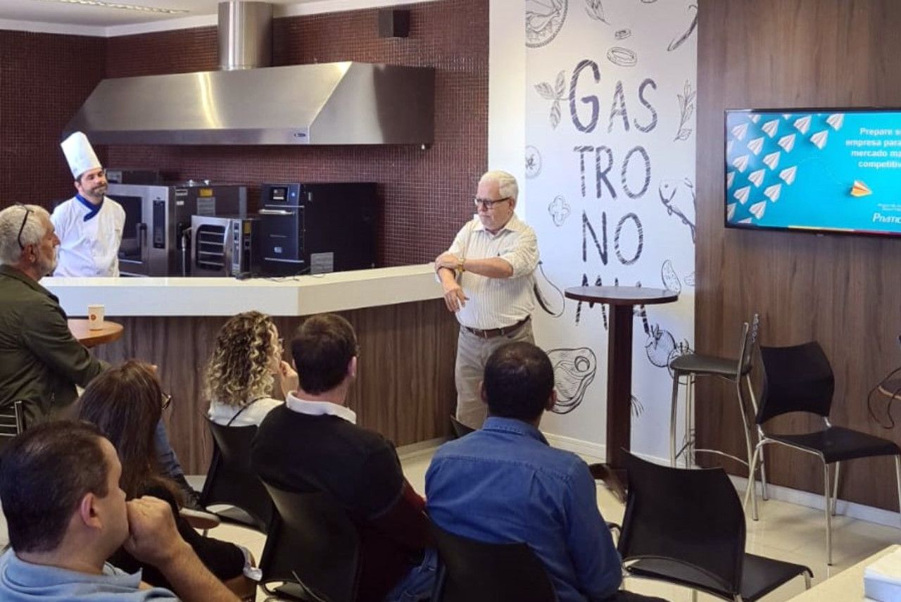 Um grupo de pessoas está sentado em frente a uma parede que diz gas tro no