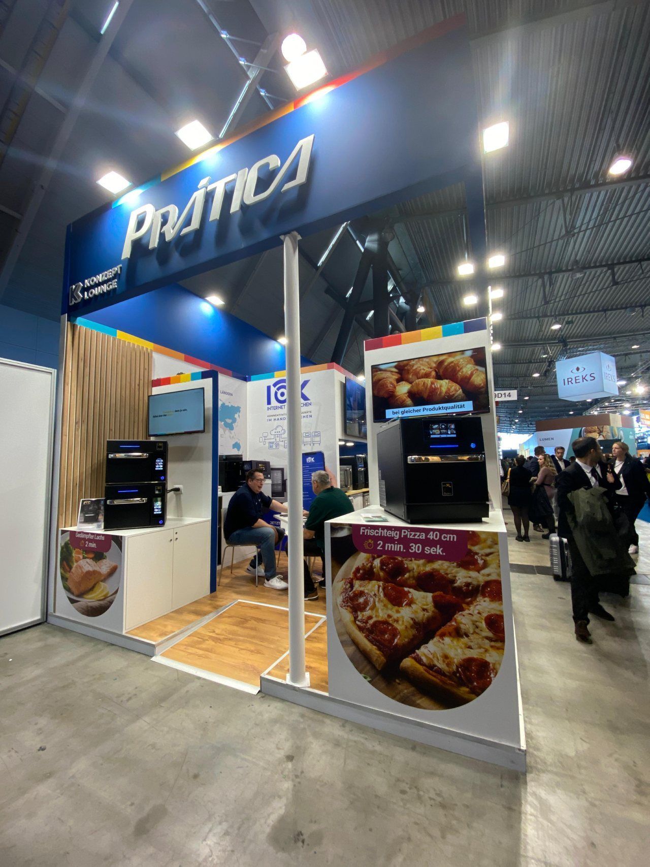 Um grupo de pessoas está em volta de um estande que diz pratica