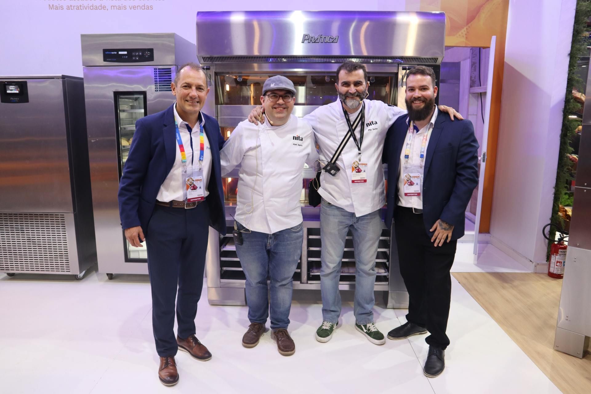Um grupo de homens está posando para uma foto em frente a um forno de aço inoxidável.