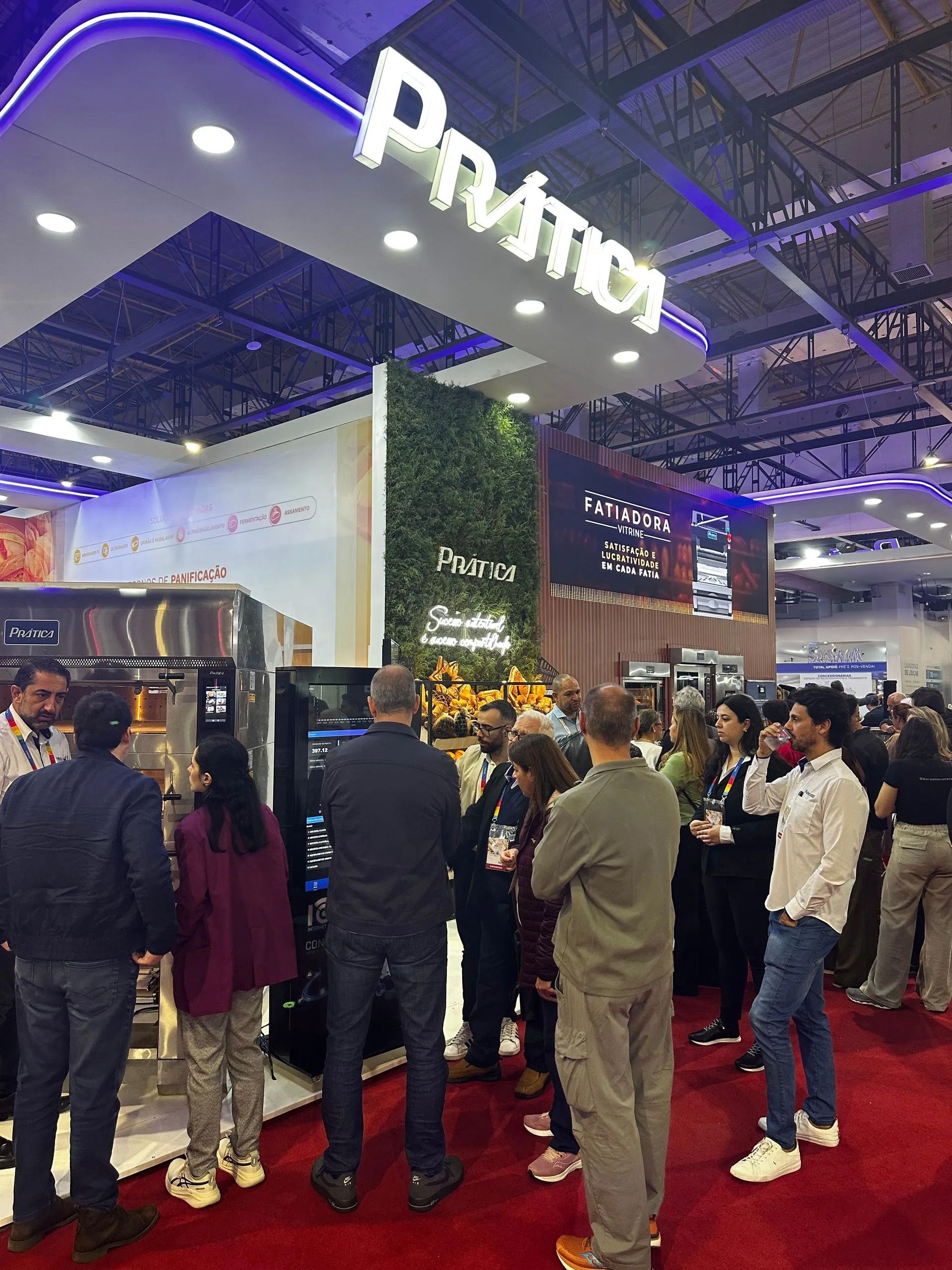 Um grupo de pessoas está em volta de um estande em uma convenção.