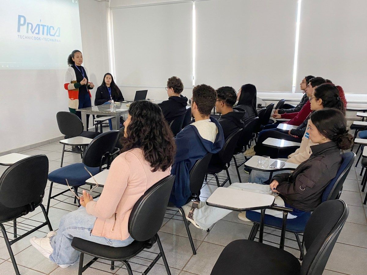 Um grupo de pessoas está sentado em cadeiras em uma sala de aula.
