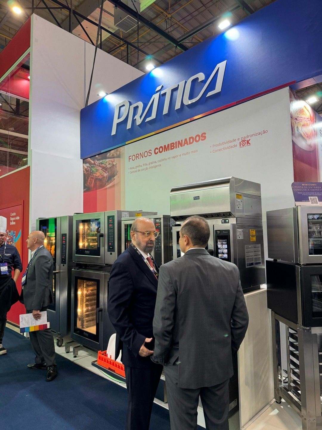 Um grupo de homens está em frente a uma exposição de fornos.