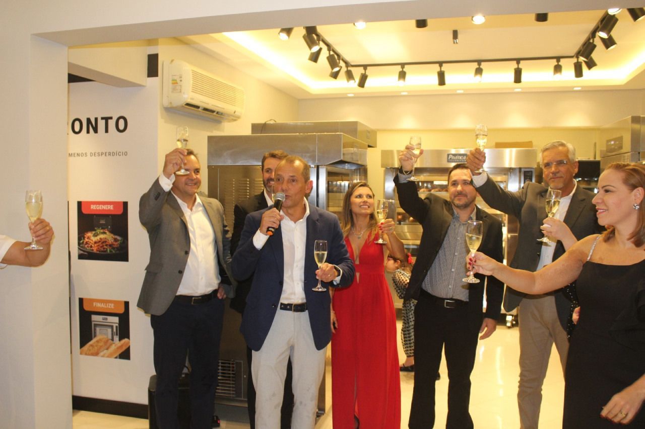 Um grupo de pessoas está em uma sala brindando com taças de champanhe.