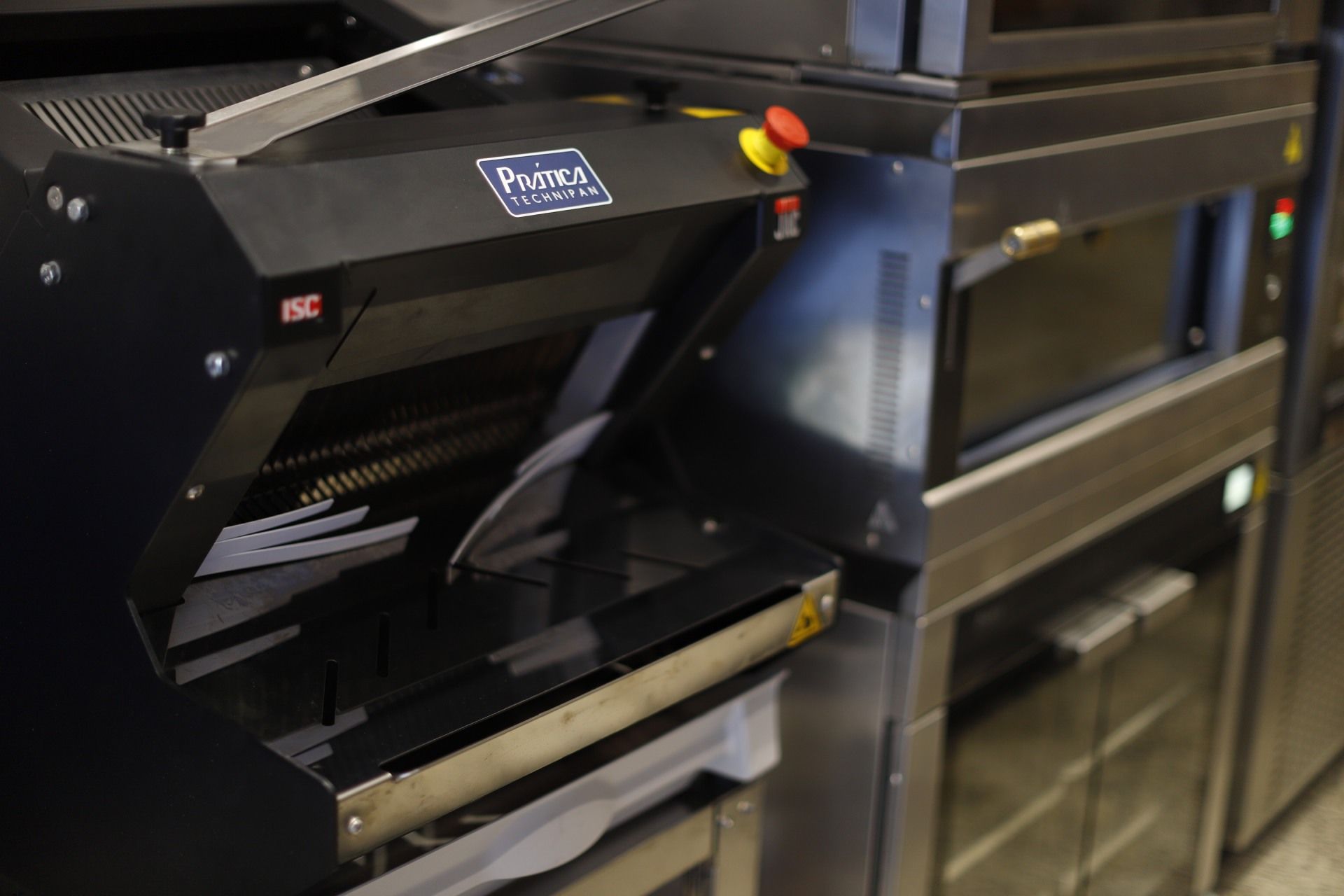 Máquina de fatiar pão com o logotipo Pastur em uma cozinha comercial.