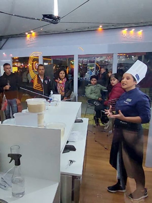 Uma mulher com um chapéu de chef está parada na frente de um grupo de pessoas.