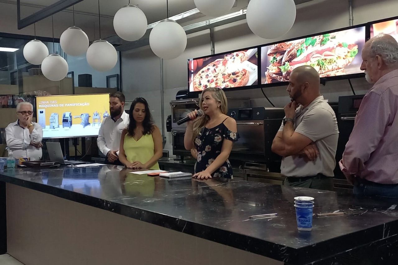 Um grupo de pessoas está em pé ao redor de um balcão em um restaurante.