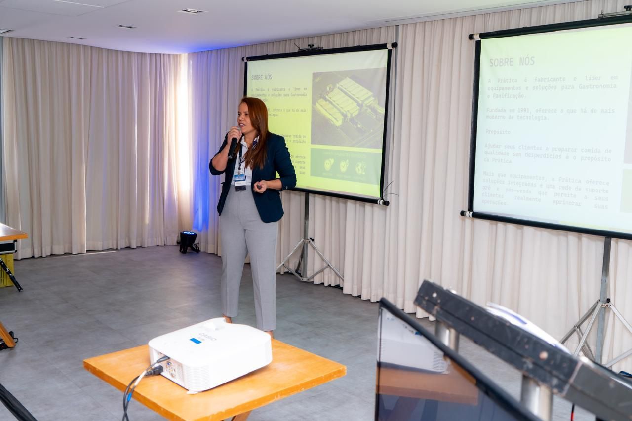 Uma mulher está fazendo uma apresentação em frente a uma tela de projetor.