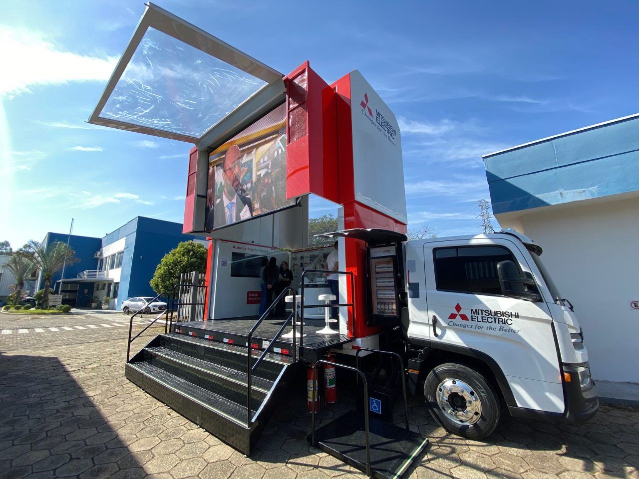 Um caminhão com um trailer acoplado está estacionado em frente a um prédio.