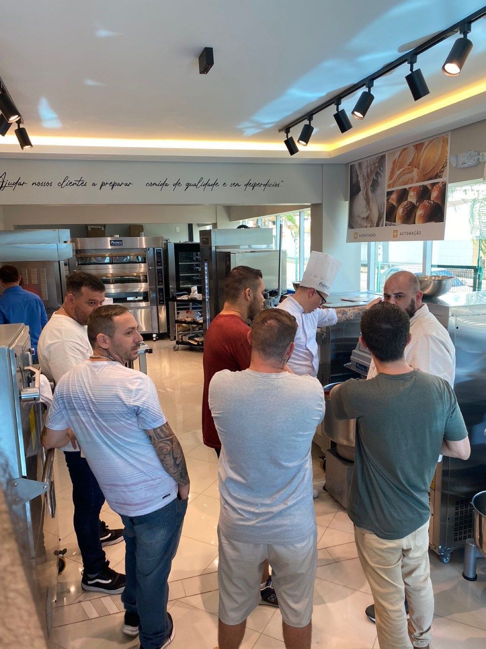 Um grupo de homens está em uma cozinha conversando entre si.