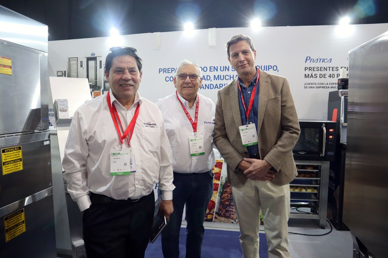 Três homens estão posando para uma foto em frente a uma máquina.