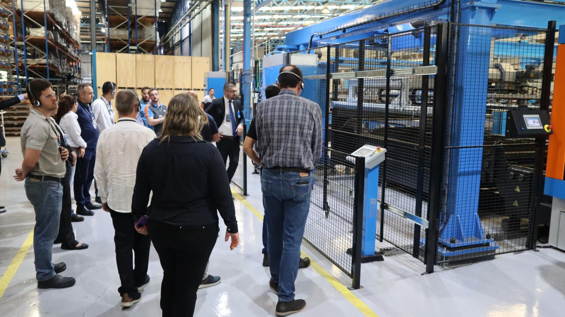 Um grupo de pessoas está caminhando por uma fábrica.