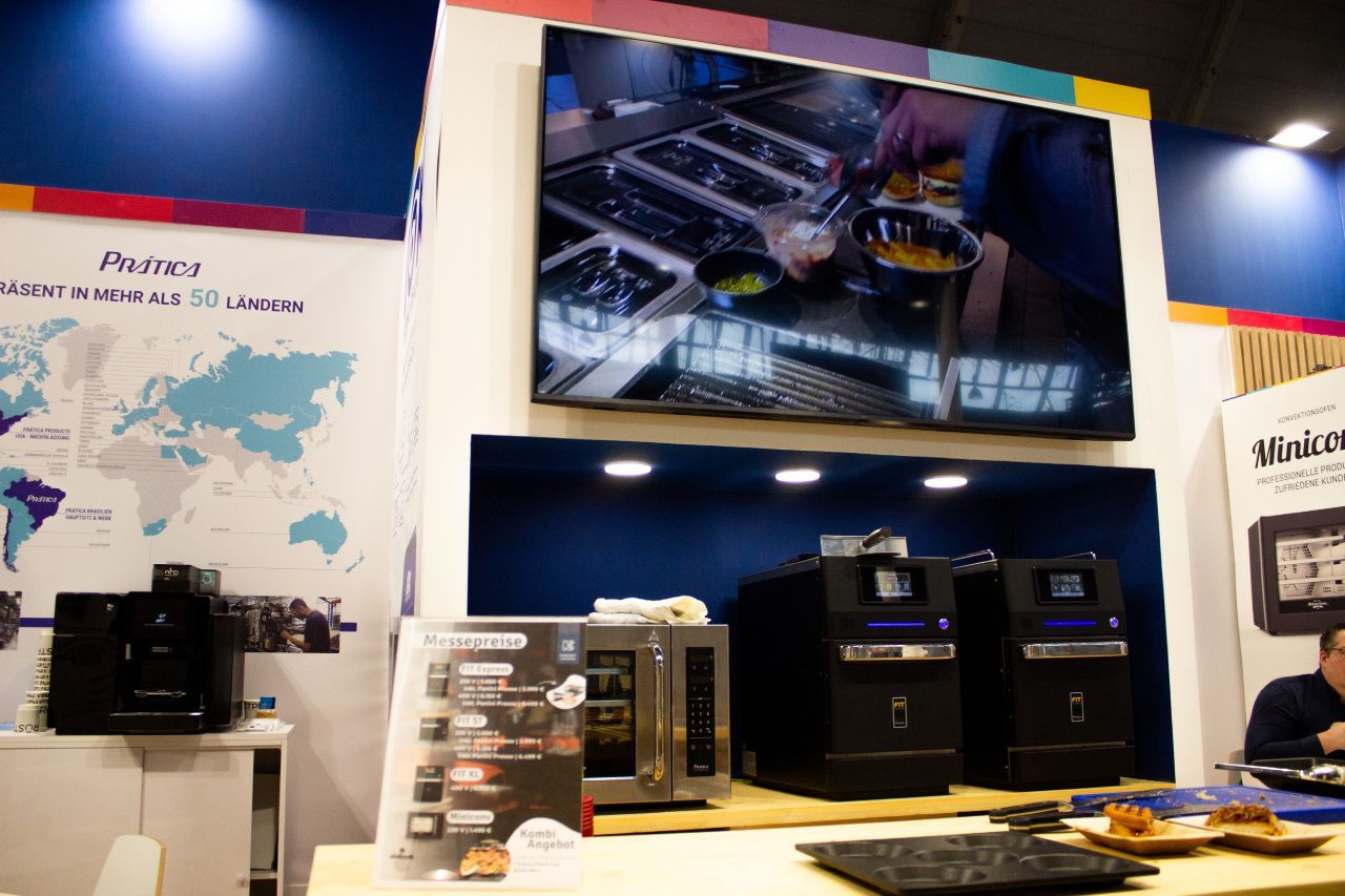 Um homem está sentado à mesa em frente a uma grande TV de tela plana.