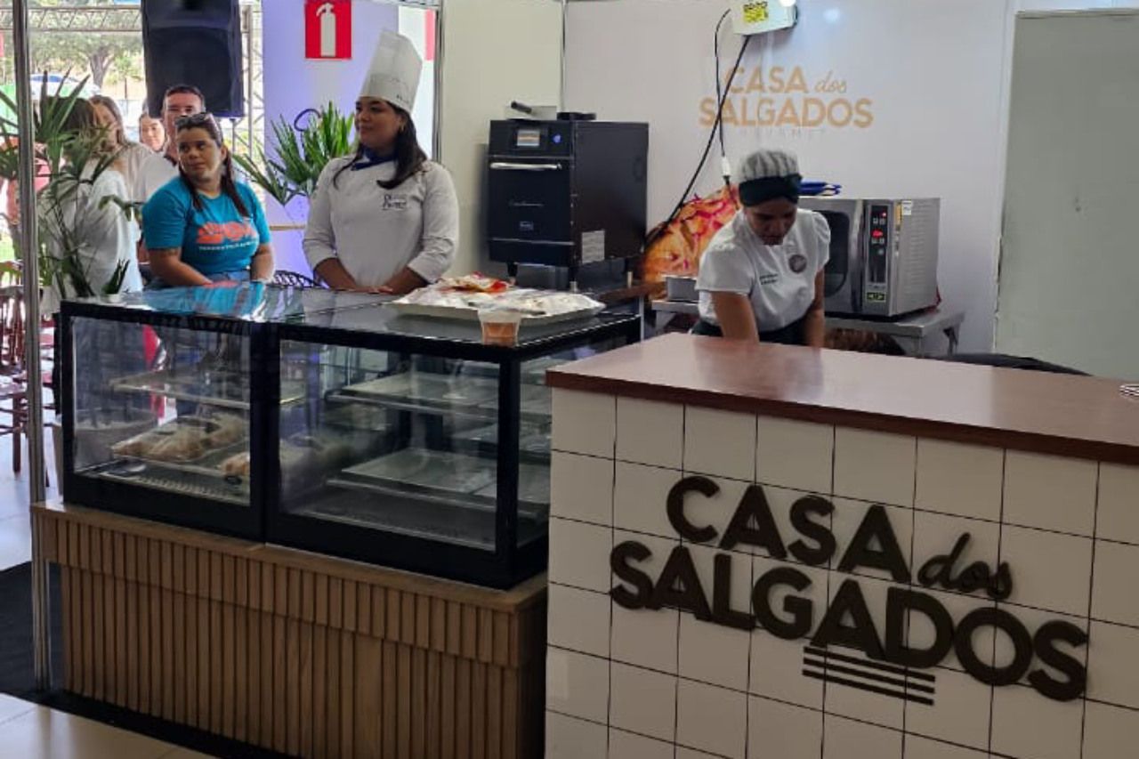 Um grupo de pessoas está em pé ao redor de um balcão em um restaurante.