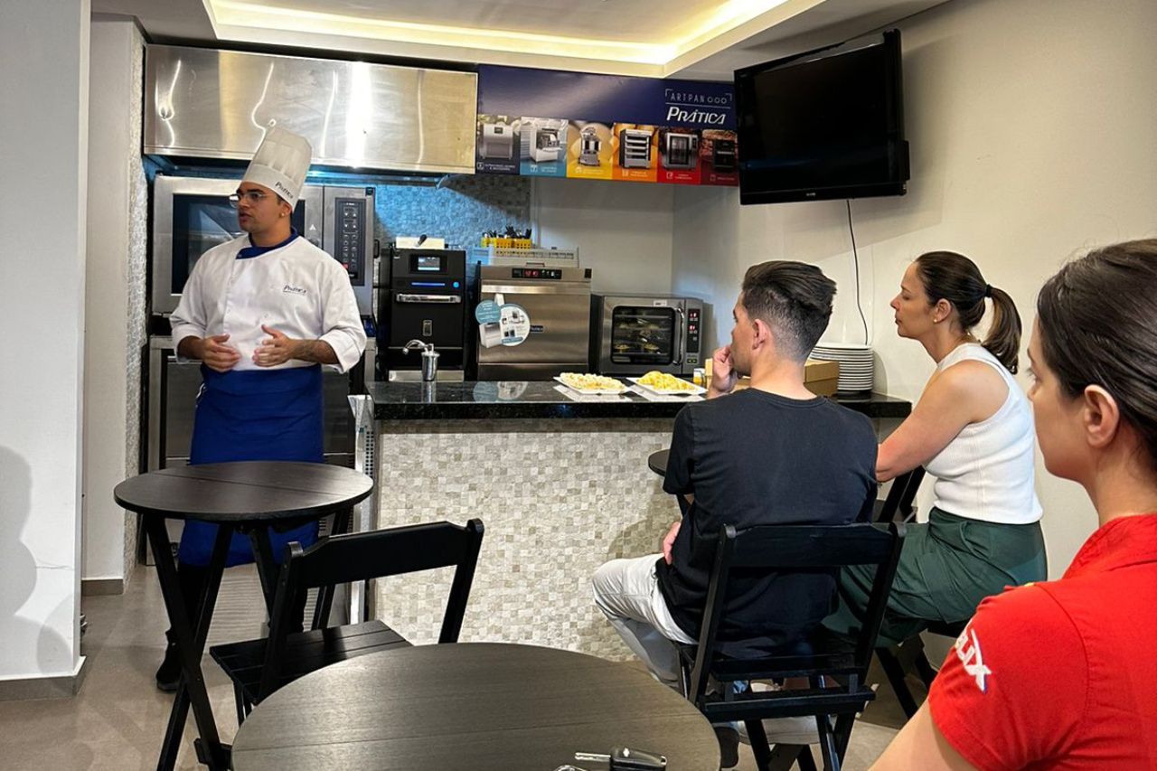 Um grupo de pessoas está sentado em mesas em uma cozinha.