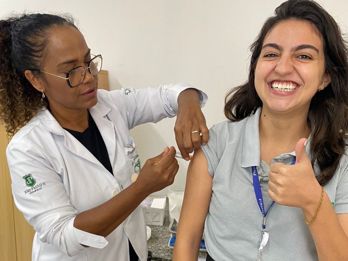Uma mulher está recebendo uma vacina de um médico e sorrindo.