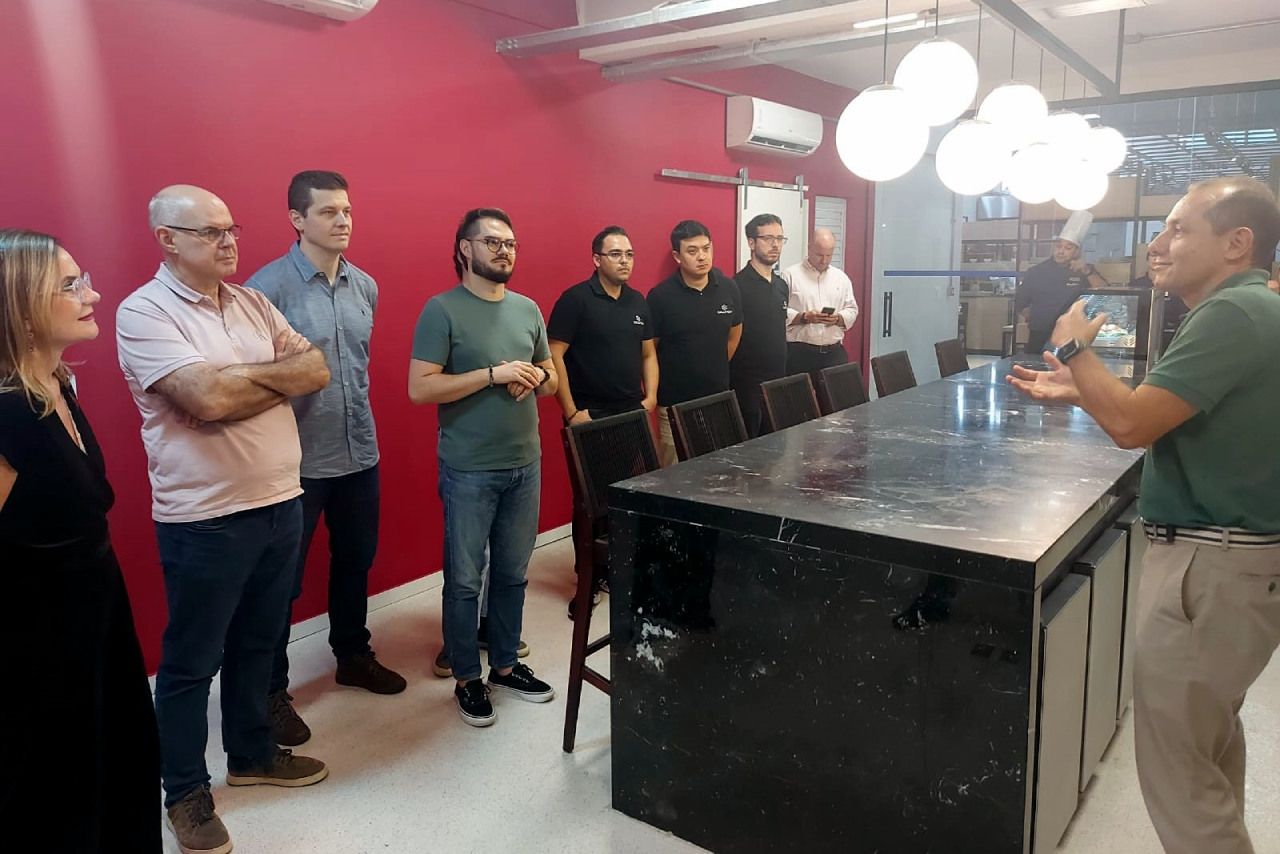 Um grupo de pessoas está em pé ao redor de uma mesa em uma sala.