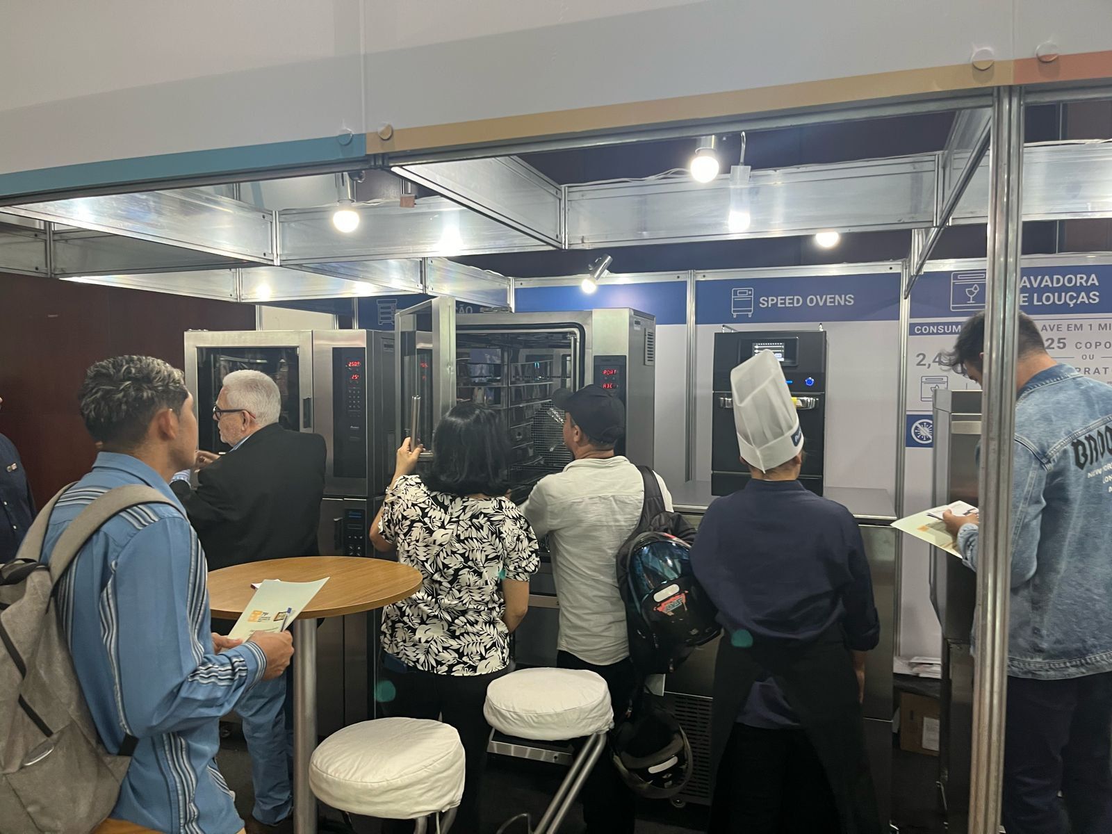 Um grupo de pessoas está em pé ao redor de uma mesa em uma sala.