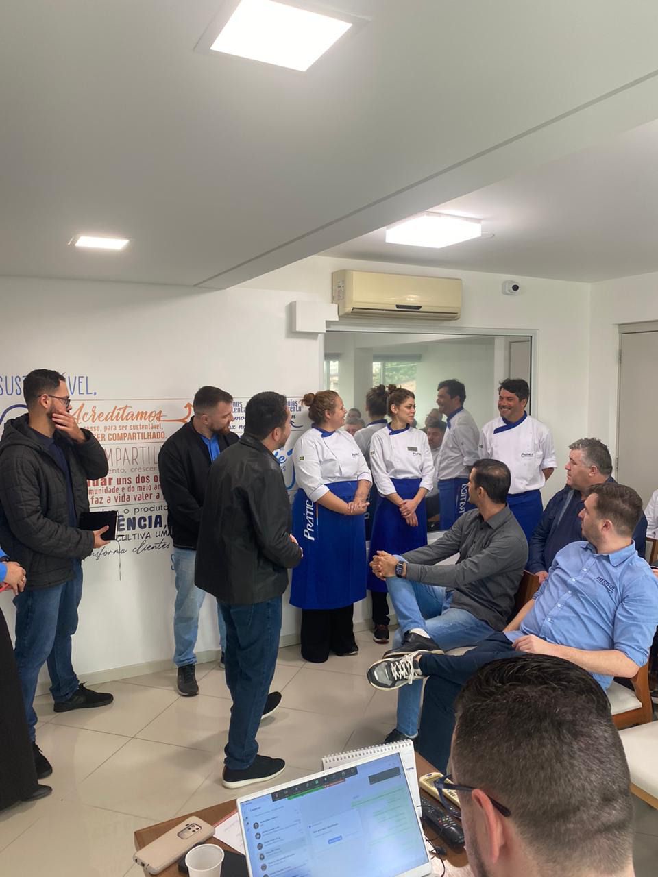 Um grupo de pessoas está em uma sala conversando entre si.