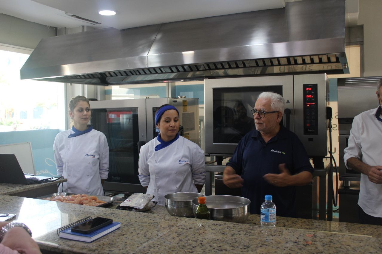 Um grupo de chefs estão em uma cozinha conversando entre si.