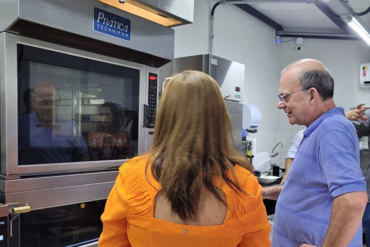 Um homem e uma mulher estão em frente a um forno.