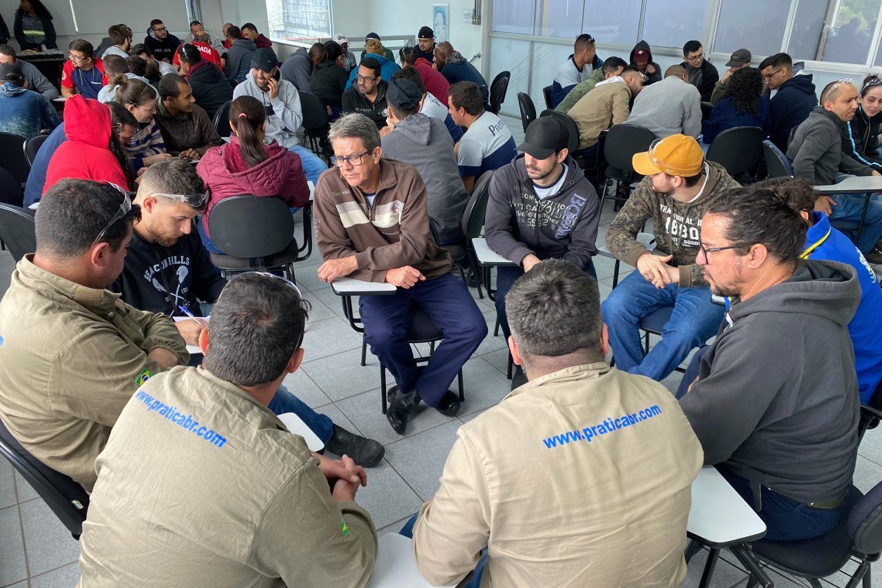 Um grupo de homens está sentado em círculo em uma sala.