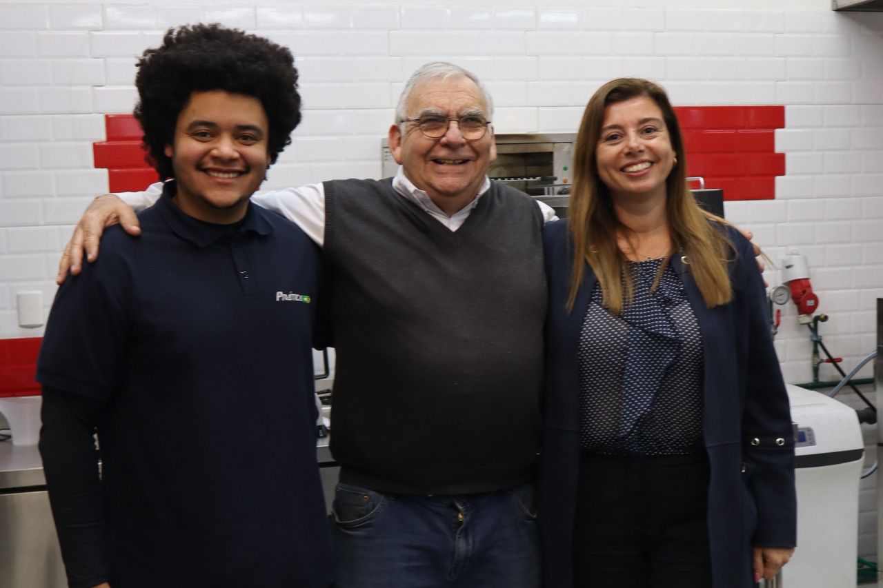 Um homem e duas mulheres posam para uma foto em uma cozinha.