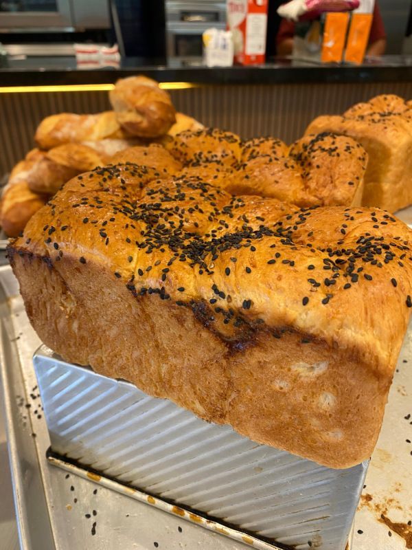 Um pedaço de pão está em cima de uma bandeja de metal sobre uma mesa.