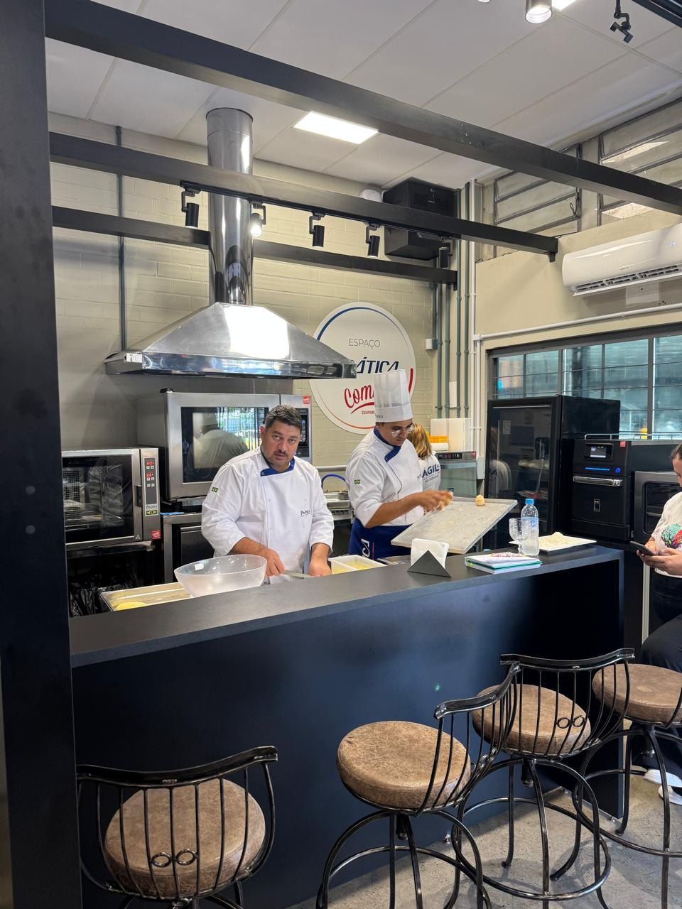 Um grupo de homens está atrás de um balcão em uma cozinha.