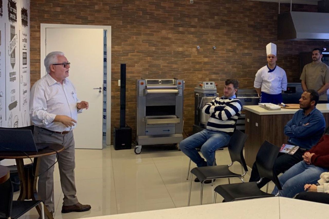 Um homem está fazendo uma apresentação para um grupo de pessoas em uma sala.