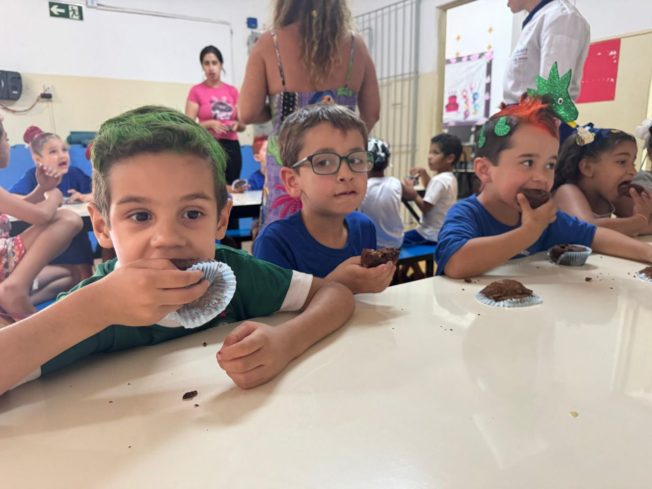 Um grupo de crianças está sentado à mesa comendo.