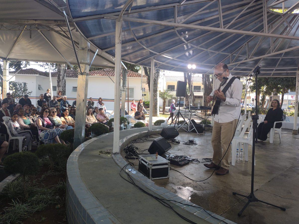 Um homem está tocando violão em um palco na frente de uma multidão.