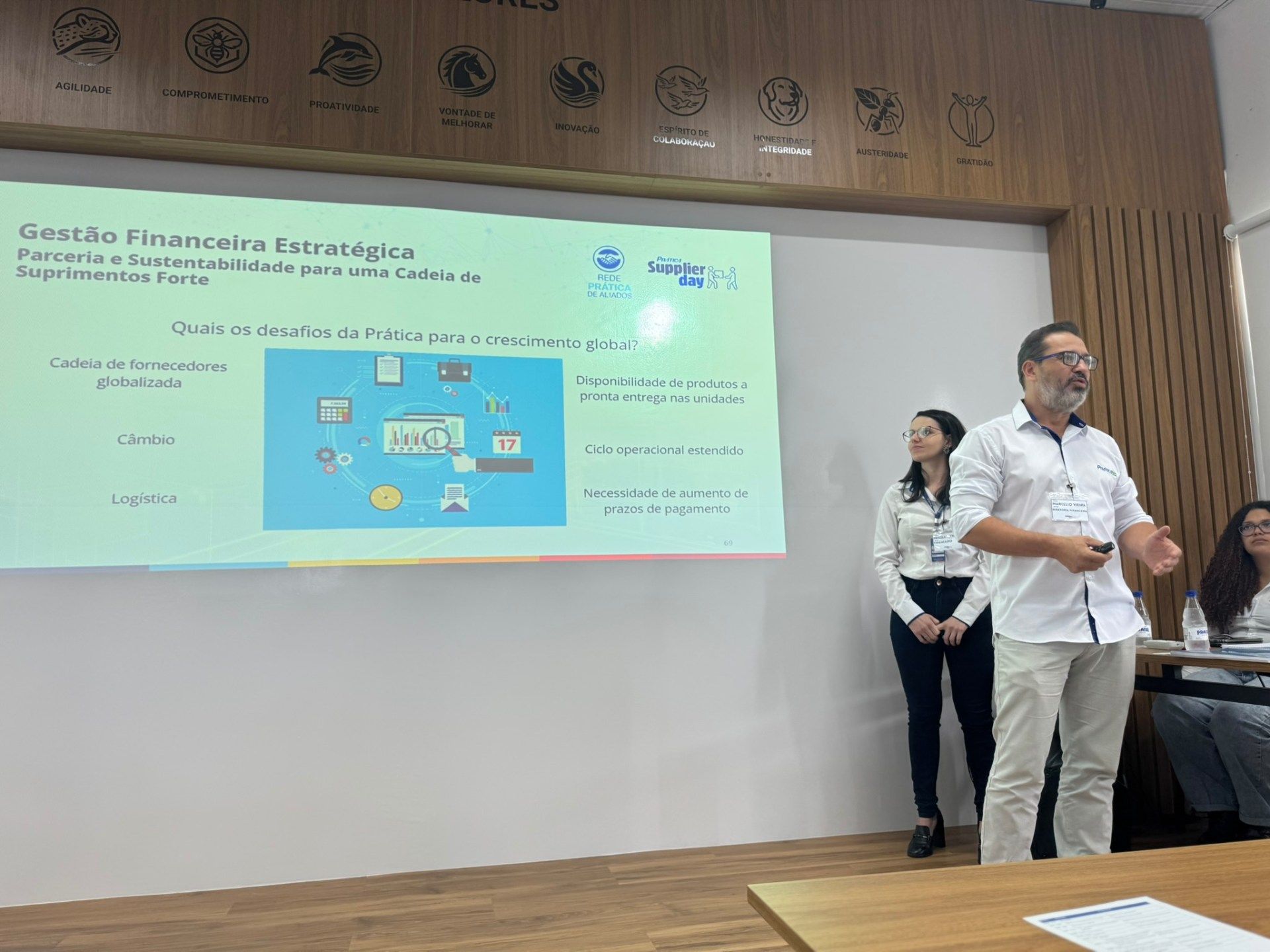 Um homem está fazendo uma apresentação em frente a uma tela grande.