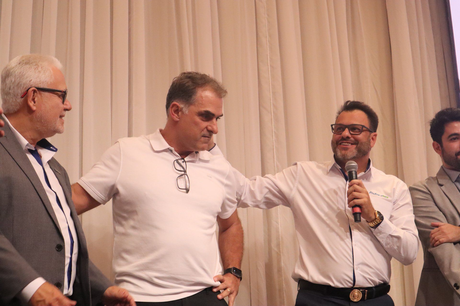 Um grupo de homens está de pé um ao lado do outro e um deles está segurando um microfone.