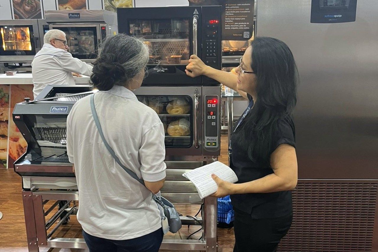 Duas mulheres estão em frente a um forno de padaria.