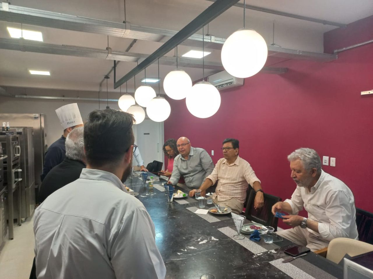 Um grupo de pessoas está sentado à mesa em uma cozinha