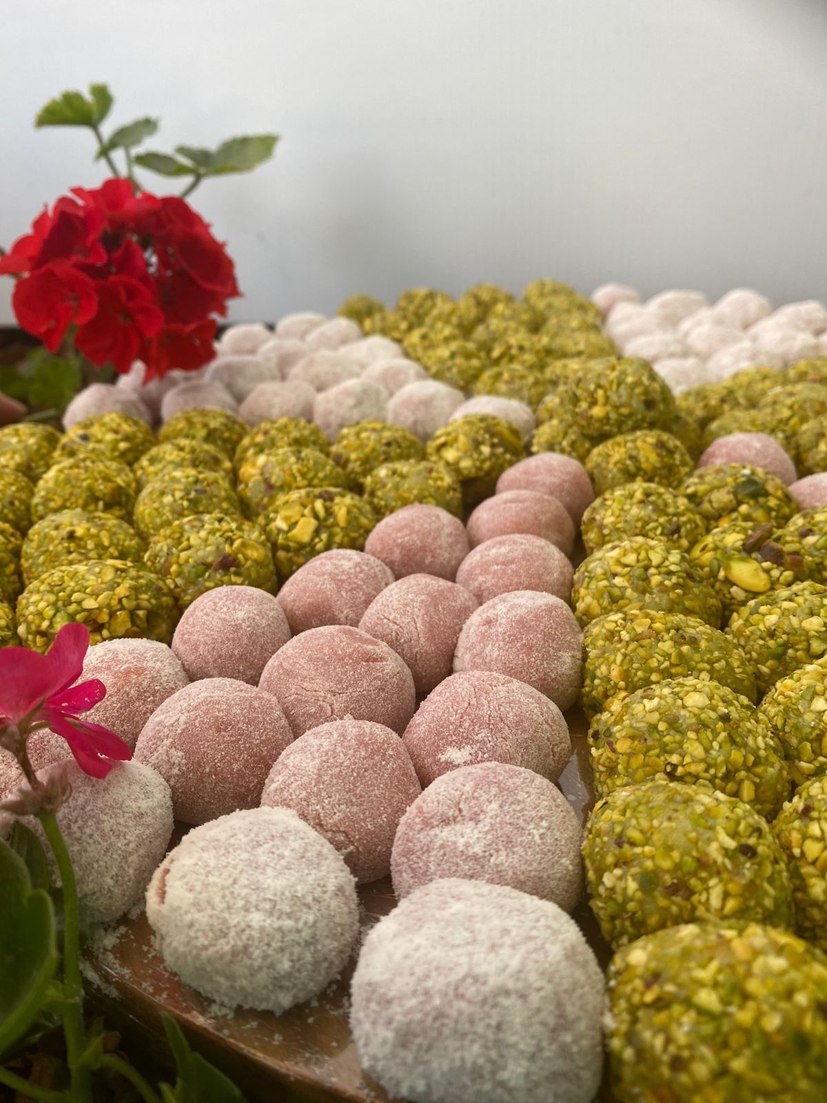 Um monte de bolas coloridas diferentes em uma mesa com uma flor no fundo