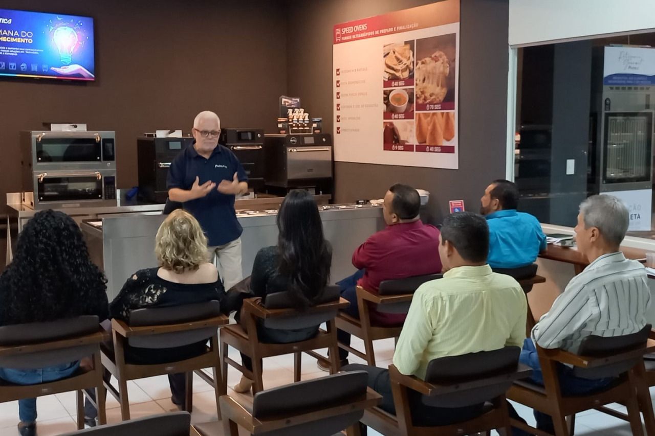Um homem está fazendo uma apresentação para um grupo de pessoas sentadas em cadeiras.