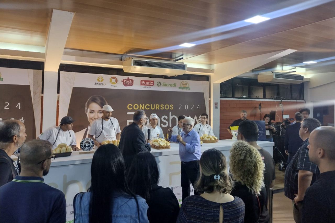 Um grupo de pessoas está em uma sala assistindo a uma apresentação.