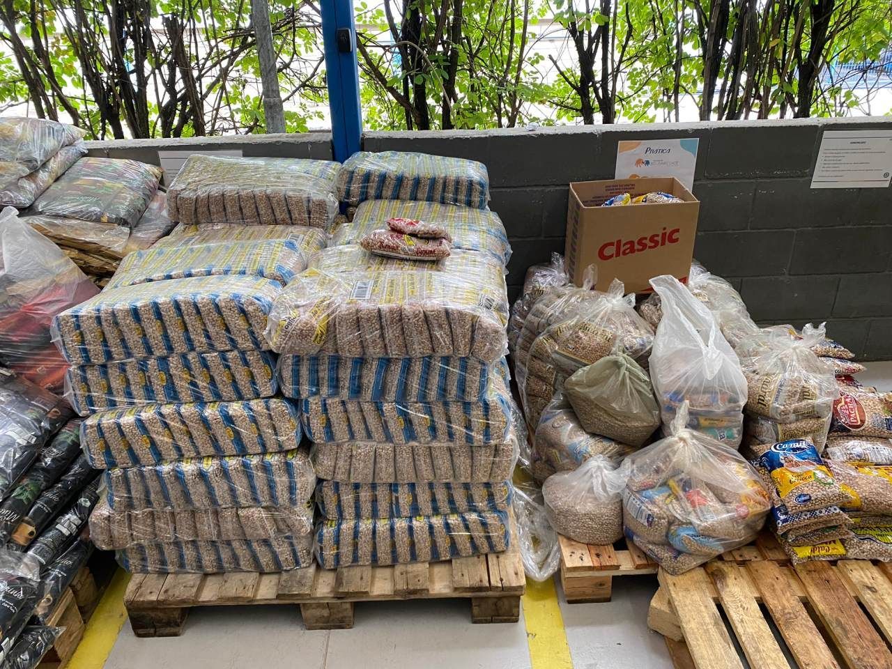 Um monte de sacos de comida empilhados uns sobre os outros em paletes de madeira.