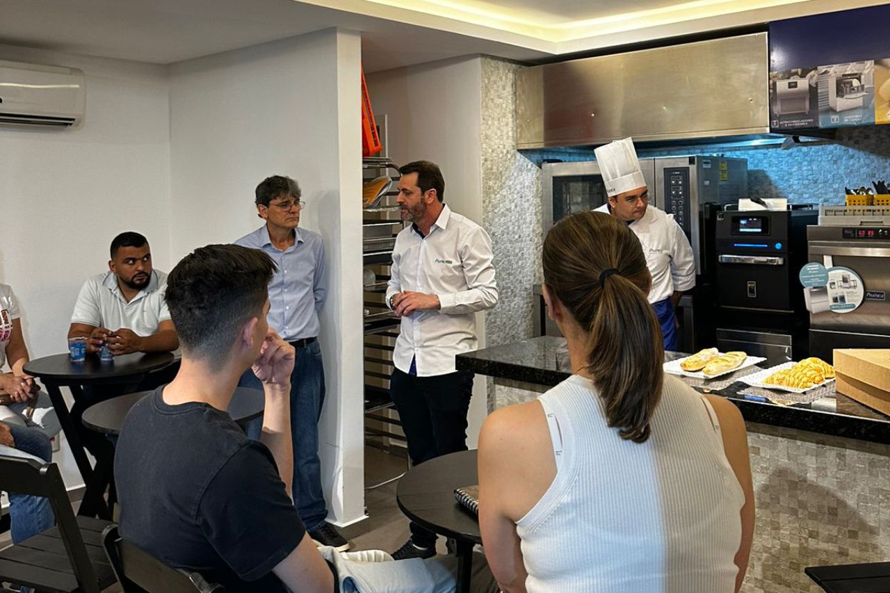 Um grupo de pessoas está sentado em mesas em uma cozinha.