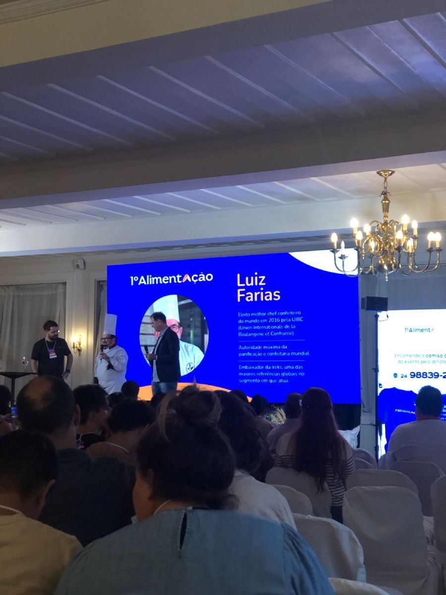 Um grupo de pessoas está sentado em frente a uma tela que diz luiz faras