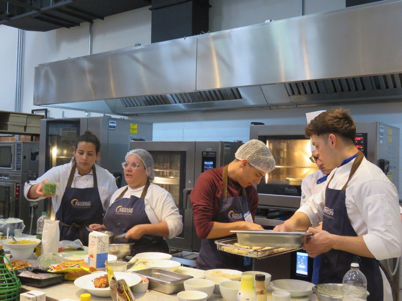 Um grupo de chefs está preparando comida em uma cozinha.