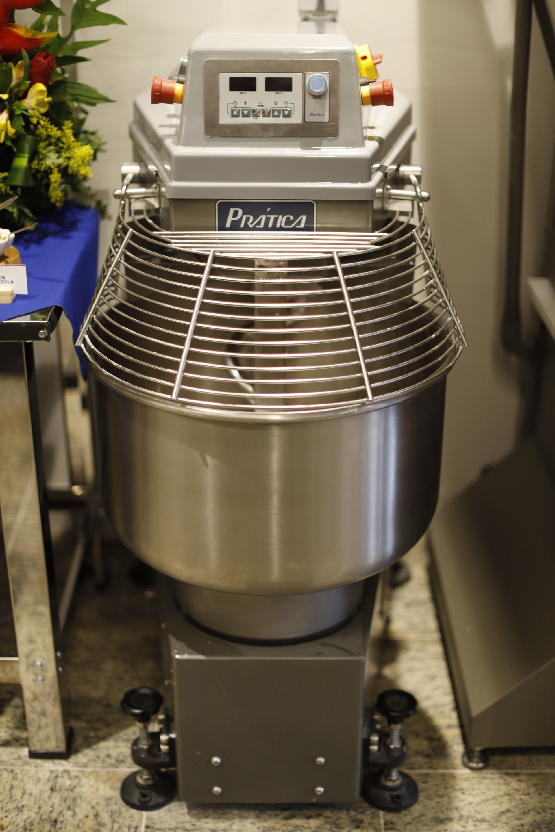 Uma grande batedeira comercial com tigela de aço inoxidável e proteção.