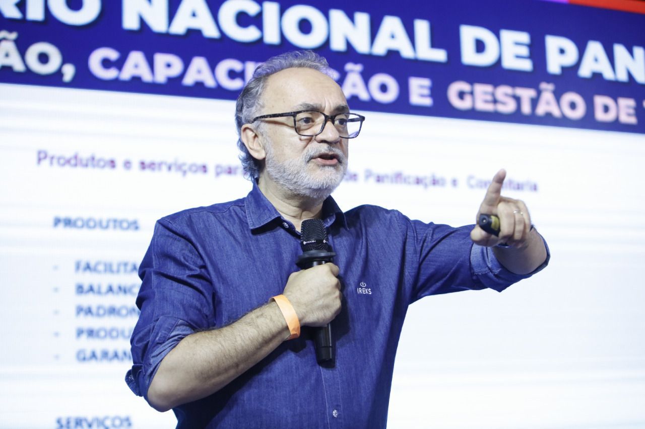 Um homem de óculos e barba está falando em um microfone