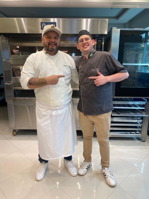 Dois homens estão posando para uma foto em frente a um forno.