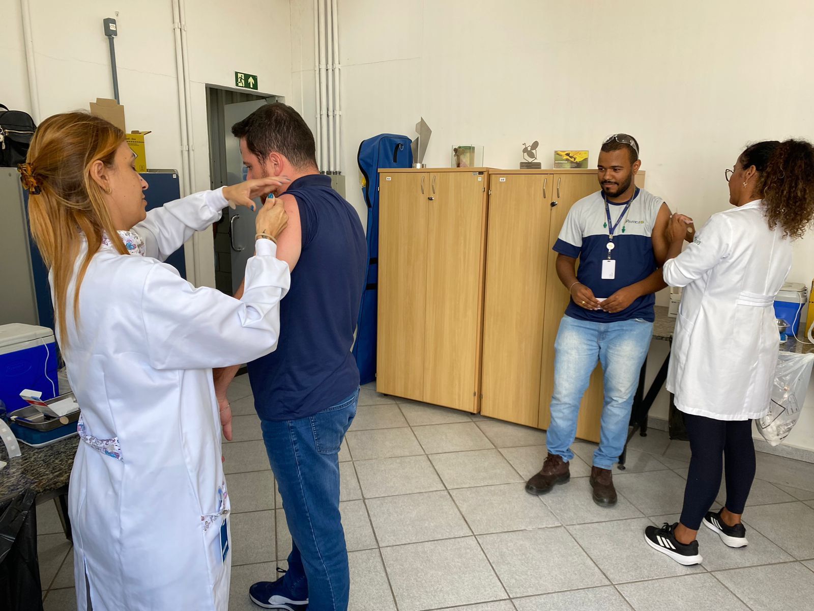 Uma mulher está dando vacina a um homem em uma sala.
