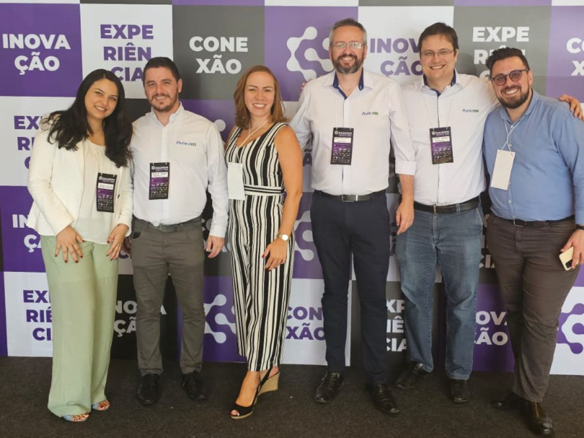 Um grupo de pessoas posando em frente a uma parede que diz inovacao